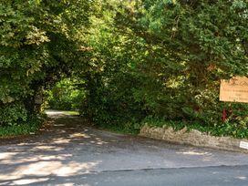 A pathway leading through trees with a sign at Milton Manor in Milton On Stour