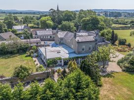 An outdoor view of a house with garden and trees at Milton Manor in Milton On Stour