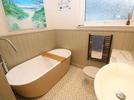 A bathroom with a bathtub, toilet, sink, and towel rack at The Poop Deck in Coverack