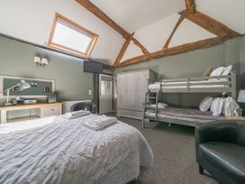 A bedroom with a double bed, bunk beds, wardrobe, desk, black chair, carpet, and exposed wooden beams at The Boars Head Pub in Bishops Castle