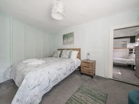 A bedroom with a double bed bedside table and open doorway showing bunk beds at The Boars Head Pub in Bishops Castle