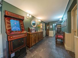 A hallway with a vintage videogame machine a wooden sideboard a bench and a sign pointing to restaurant and bar at The Boars Head Pub in Bishops Castle