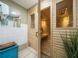 A wooden sauna room with an open door next to a tiled wall and a blue cabinet with a wooden tray at The Boars Head Pub in Bishops Castle