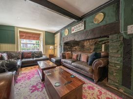 A sitting room with leather sofas wooden tables and a decorated stone fireplace at The Boars Head Pub in Bishop's Castle