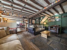 A pub seating area with sofas, armchairs, wooden tables, and a bar in the background at The Boars Head Pub in Bishops Castle