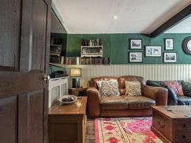 A living room with a brown leather couch pillows wooden furniture and framed pictures on the wall at The Boars Head Pub in Bishops Castle