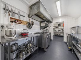 A commercial kitchen with stainless steel counters pots pans knives and a stove at The Boars Head Pub in Bishops Castle