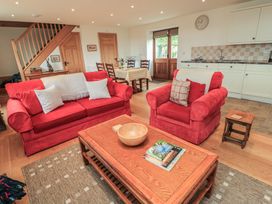 A living room with red furniture and a dining area at Bramble Cottage in Babcary near Lydford-On-Fosse