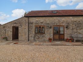 An outdoor area with a stone wall and wooden doors at Badger Cottage in Lydford-On-Fosse