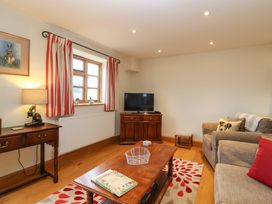 A living room with a sofa, television, and coffee table at Badger Cottage, Lydford-On-Fosse