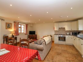 A living room with a sofa and kitchen area at Badger Cottage in Lydford-On-Fosse