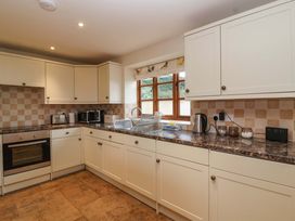 A kitchen with cabinets, oven, and appliances at Badger Cottage in Lydford-On-Fosse