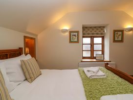 A bedroom with a bed and window at Badger Cottage in Lydford-On-Fosse