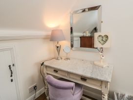 A vanity table with a mirror and lamp in a bedroom at Dove Cottage in Pickering