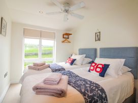 A bedroom with two beds and a window at 7 Ocean's Edge in Thurlestone