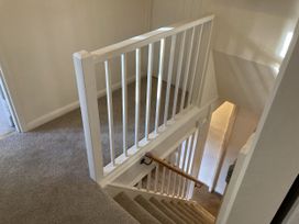 A hallway with a staircase and railing at Yew Tree Cottage in Stoke Fleming