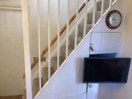 A staircase with a clock and television at Yew Tree Cottage Stoke Fleming
