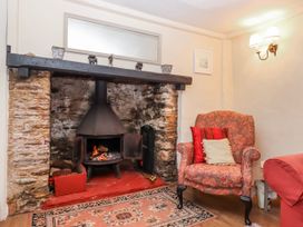 A living room with a fireplace and armchair at Yew Tree Cottage in Stoke Fleming