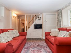A living room with sofas and a clock at Yew Tree Cottage in Stoke Fleming