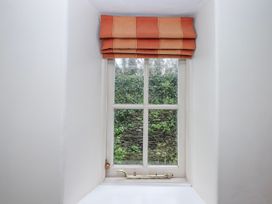 A window with a view of a stone wall and plants at Yew Tree Cottage in Stoke Fleming