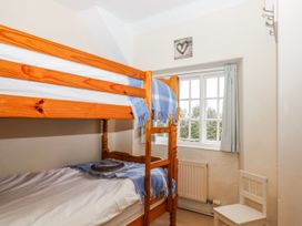 A bedroom with a bunk bed and window at Yew Tree Cottage Stoke Fleming