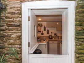 A kitchen with a sink and stove visible from the entrance at Yew Tree Cottage in Stoke Fleming