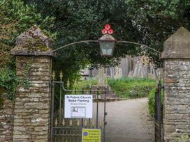 A gate with a sign and gravestones at St Peters Church in Stoke Fleming