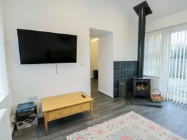 A living room with a television and a wood stove at 2 Mountain View Talwrn near Llangefni