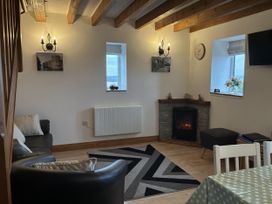 A living room with a fireplace and sofa at Ysgubor Ddegwm Bach LLanddona near Beaumaris