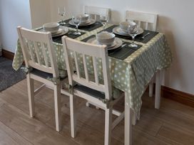 A dining room with a table set for four at Ysgubor Ddegwm Bach in Llanddona near Beaumaris