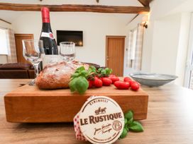 A kitchen with a cutting board, wine, cheese, and vegetables at Crabtree Cottage, Suffield near Scalby