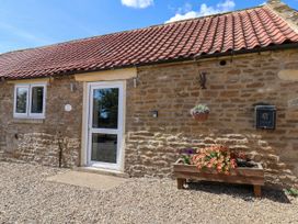 An entrance to a cottage with a door, window, and flower box at Crabtree Cottage Suffield near Scalby