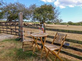 A table with two chairs in an outdoor setting with sheep in the background at Crabtree Cottage Suffield near Scalby