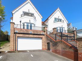 A two-story house with white walls and red roof tiles with a garage below and stairs leading up to balconies at Cambrie in Tenby