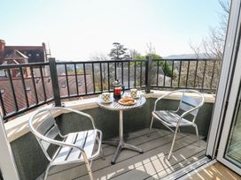 A balcony with two metal chairs a small round table with mugs a French press and pastries at Cambrie in Tenby