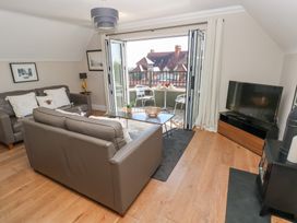A living room with two brown sofas a glass coffee table a television and an open door leading to a balcony at Cambrie in Tenby