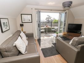 A living room with leather sofas a glass coffee table a television and balcony doors open to an outdoor seating area at Cambrie in Tenby