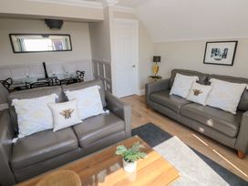 A living room with two gray sofas with cushions and a wooden coffee table with a plant at Cambrie in Tenby