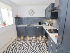 A kitchen with grey cabinets a tiled floor and countertop appliances at Cambrie in Tenby