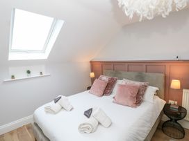 A bedroom with a bed with pink pillows and towels on it near a skylight window and bedside tables with lamps at Cambrie in Tenby