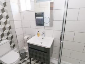 A bathroom with a toilet a sink with a cabinet a mirror a towel radiator a soap dispenser and a shower at Cambrie in Tenby