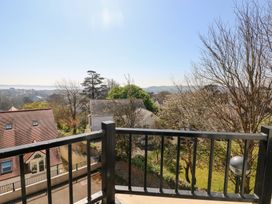 A view from a balcony with black railings overlooking houses trees and distant hills at Cambrie in Tenby