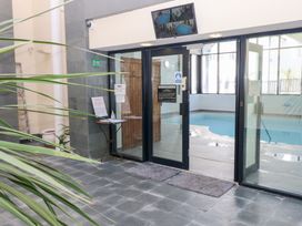 Entrance to an indoor swimming pool area with glass doors mats and potted plants at Cambrie in Tenby
