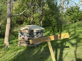A bug hotel made of stacked wooden pallets and natural materials in a grassy area with a wooden sign reading bug hotel vacancies at The Farmhouse in Newport Pembrokeshire