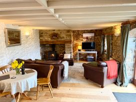 A living room with a sofa, dining table, and television at Stable Cottage in Newport, Pembrokeshire