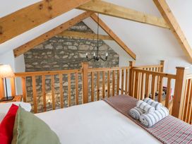 A bedroom with a bed, towels, and wooden features at West End Cottage Newport, Pembrokeshire