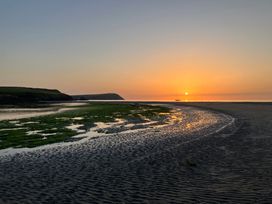 A beach at sunset with a boat on the water at West End Cottage, Newport, Pembrokeshire