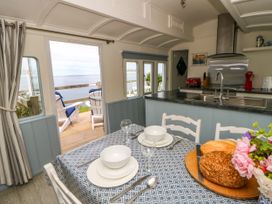 A kitchen with a dining table and chairs at Clifftop Carriage in Aberporth, Ceredigion