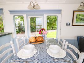 A dining room with a table set with bowls and a flower vase at Clifftop Carriage Aberporth, Ceredigion