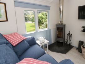 A living room with a sofa and a wood stove at Clifftop Carriage, Aberporth, Ceredigion